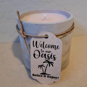 Example of a custom tag - cardstock material with printed Welcome to Our Oasis and palm trees tied to a candle with twine.